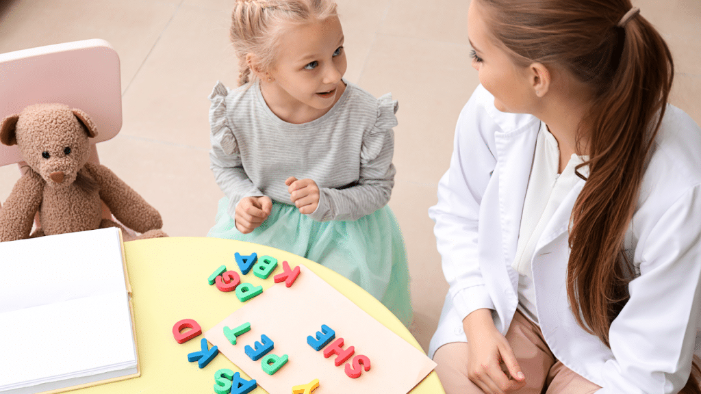 Speech pathologist using colorful letters to aid communication with a young girl.